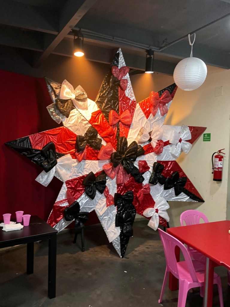 Laços e coroas artesanais feitos com malha deco metálica dispostos sobre uma mesa.