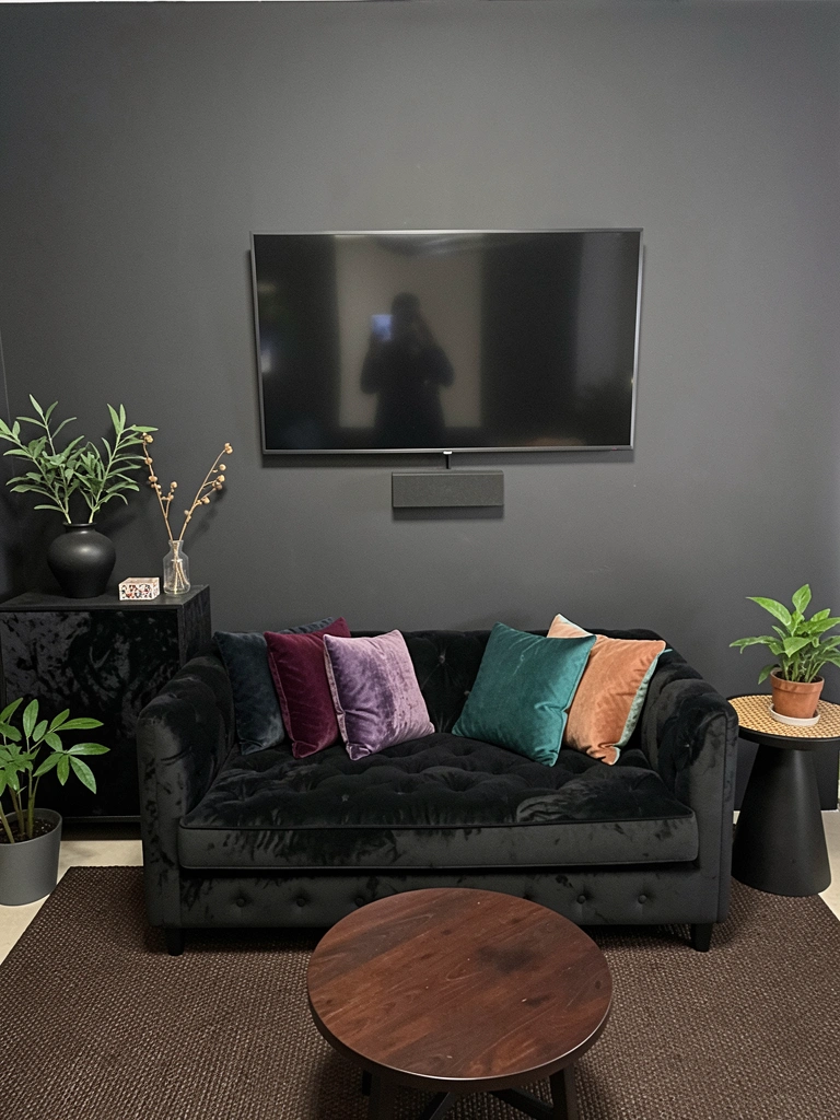 Sofá preto de veludo com almofadas coloridas em sala de estar
