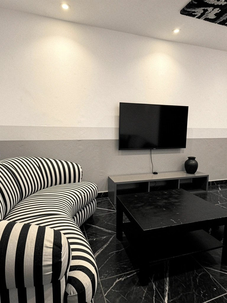 Sala em preto e branco com sofá listrado, paredes brancas e mesa preta